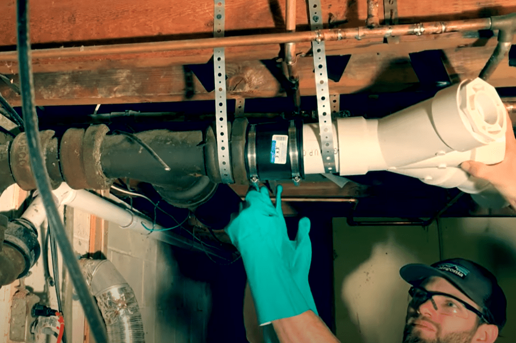 Install your "Fernco" Flexible coupling over the existing cast iron pipe and the new PVC pipe and tighten the straps