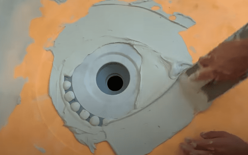Spread thinset mortar around the Kerdi Shower Drain bonding flange, removing any excess.  