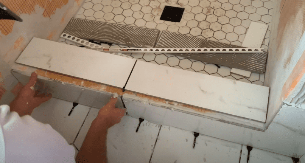 Install tiles on the front face of the shower curb by applying firm, even pressure