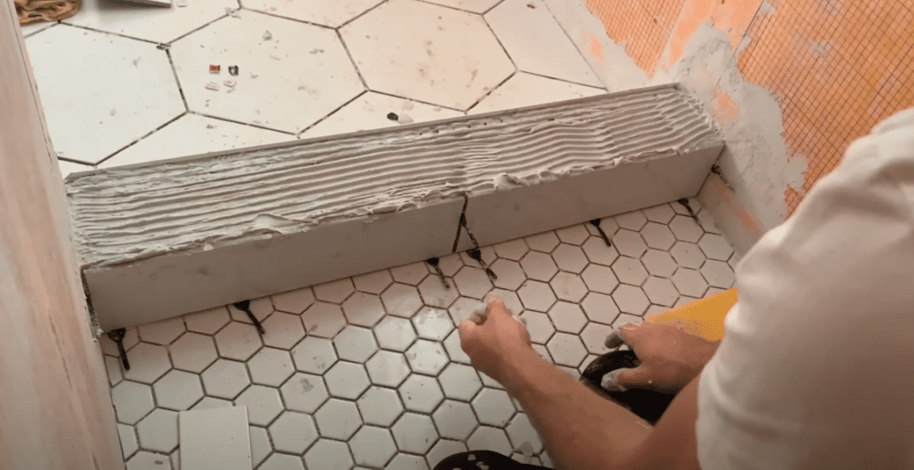 Install the shower curb tiles on the inside of the shower curb. Be sure to use spacers as shown. 