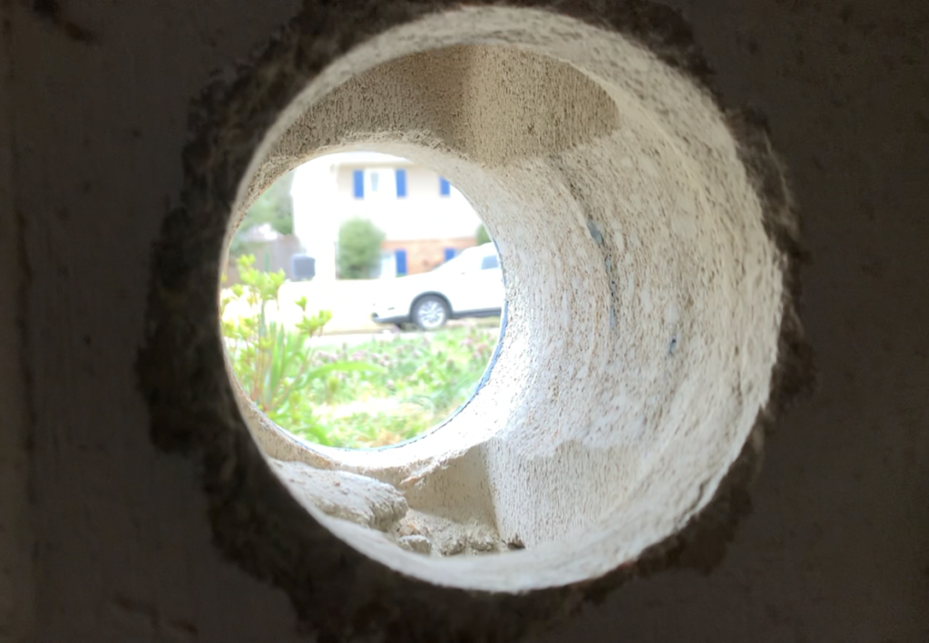 The hole left after core drilling through the concrete or cinderblock foundation