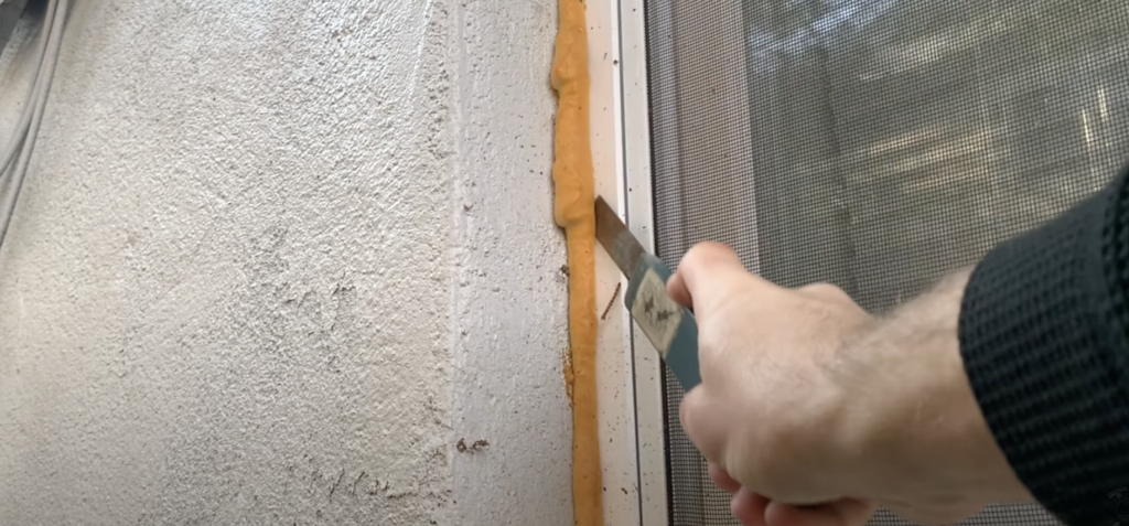 Cut off any excess spray foam around the basement window using a utility knife