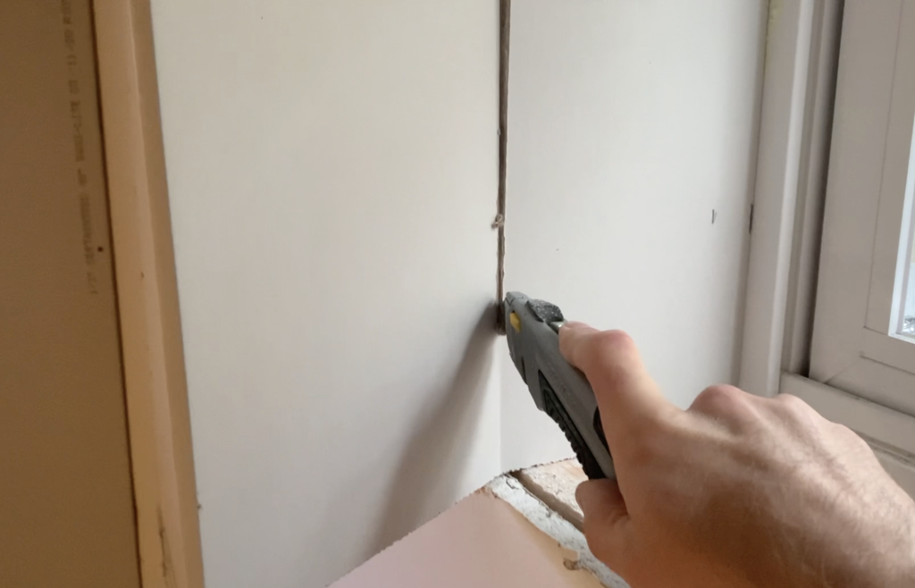 Use a utility knife to cut the side sections of drywall so that they are flush with the front of the basement wall