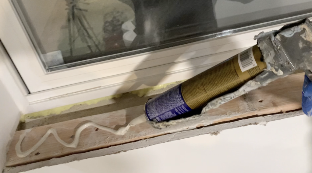 Apply construction adhesive to the basement window rough opening 