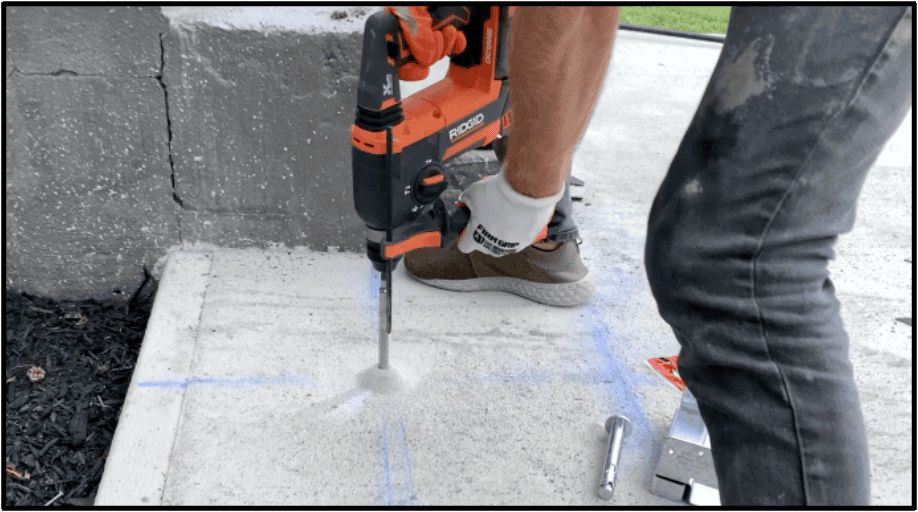 Pre drill the holes for the post anchors within the concrete using a hammer drill.